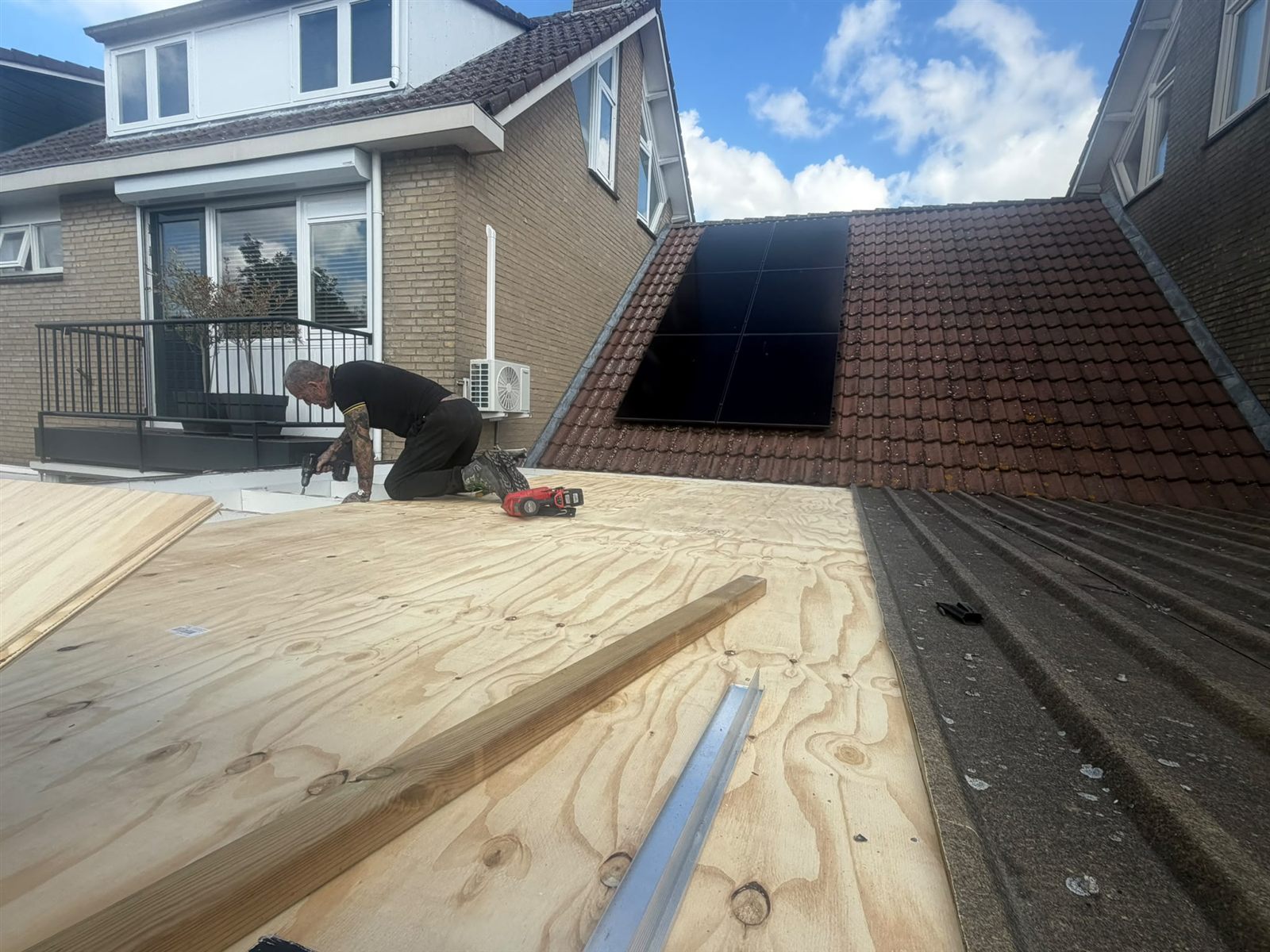 Dakdekker brengt de houten ondergrond aan op het dak van een aanbouw