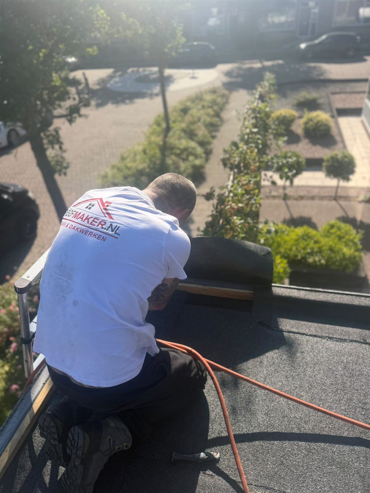Dakdekker op het bitumen dak met de omliggende woningen in beeld