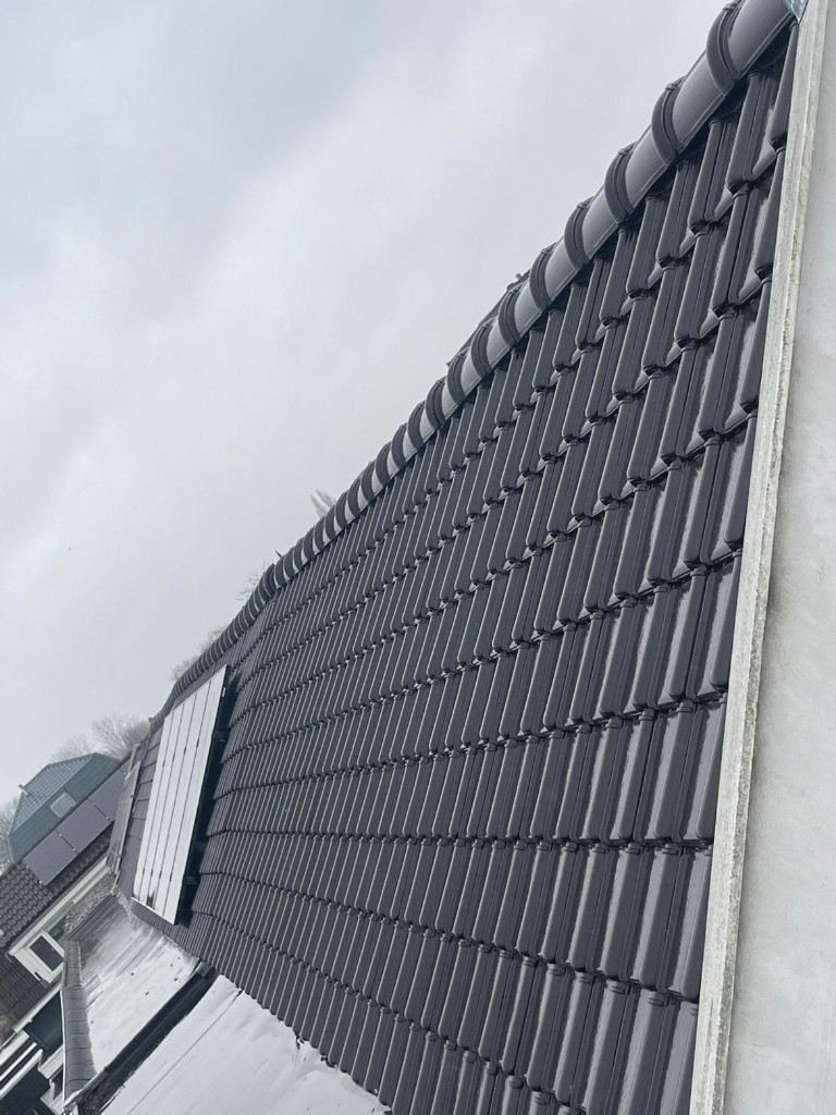 Gerenoveerd pannendak met zwarte dakpannen en zonnepanelen